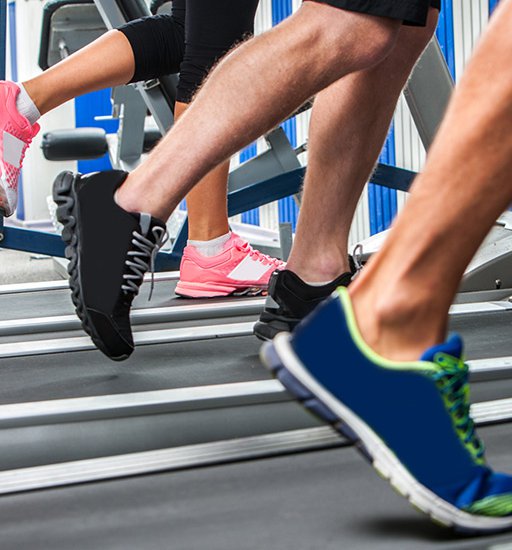 Group of legs wearing sneakers running on treadmill at sport gym.